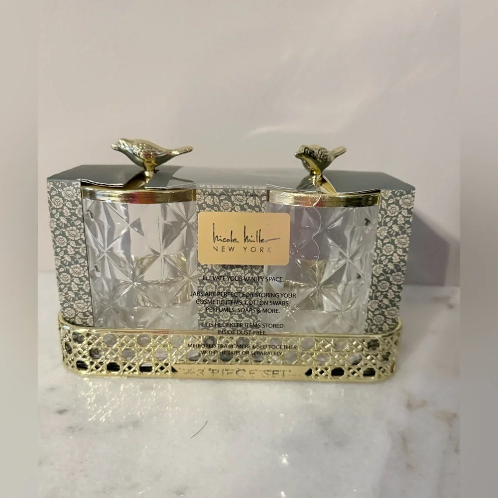 two-piece glass storage jar set with a gold bird lid and decorative tray.